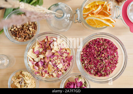 Overview of bowls with dry rose petals, pear and orange slices on wooden table Stock Photo