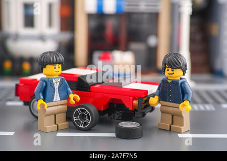 Tambov, Russian Federation - October 18, 2019 Two lego minifigures changing front wheel of a muscle car. Stock Photo