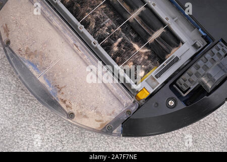 Robot vacuum cleaner clogged with hair and dust. Close up. Stock Photo