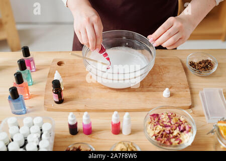 Hands of girl putting color from small plastic bottle into liquid soap mass Stock Photo