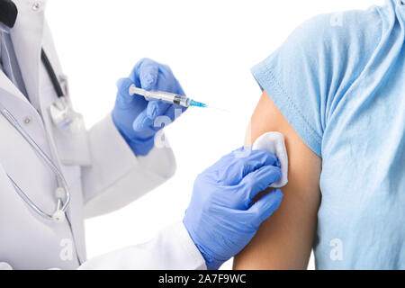 Doctor making vaccination injection, wearing blue gloves and medical gown Stock Photo