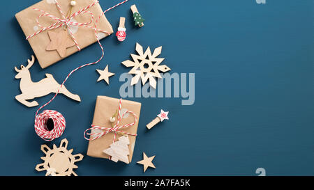 Christmas ornament on blue background. Flat lay gift boxes wrapped craft paper, striped rope, wooden handmade decorations. Xmas or New Year banner moc Stock Photo