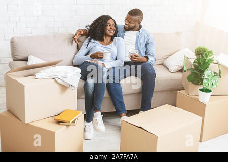Happy couple taking break, unpacking on moving day Stock Photo