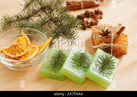 Handmade soap bars with conifer and aromatic spices and orange slices in bowl Stock Photo