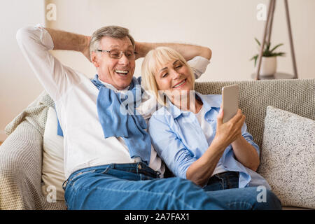 Happy mature couple using cellphone, surfing internet online Stock Photo