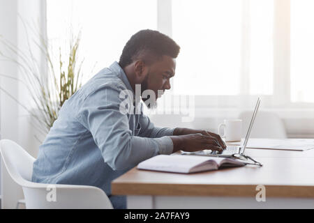 Concentrated african american manager working on laptop in office Stock Photo