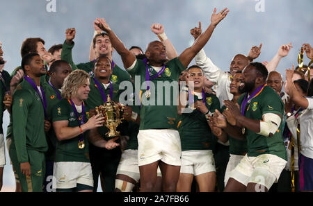 South Africa's Makazole Mapimpi (centre) celebrates as Faf de Klerk holds the Webb Ellis cup with Siya Kolisi (hidden) after South Africa win the 2019 Rugby World Cup final match at Yokohama Stadium. Stock Photo