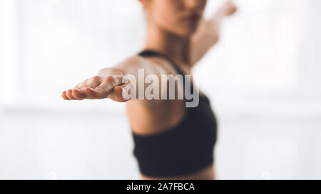 Woman exercising yoga in warrior pose, focus on hand Stock Photo