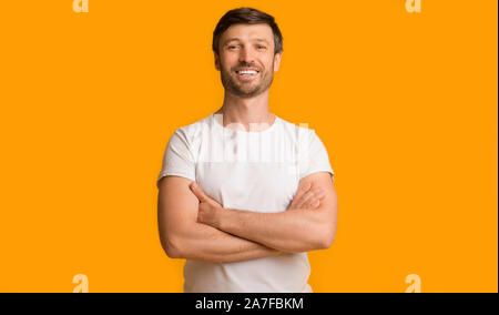 Cheerful Man Smiling Crossing Hands Standing Over Yellow Background Stock Photo