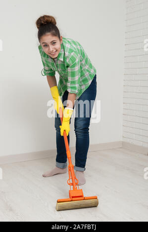 Gloved housewife with a mop washes washes the floor in the room. Stock Photo