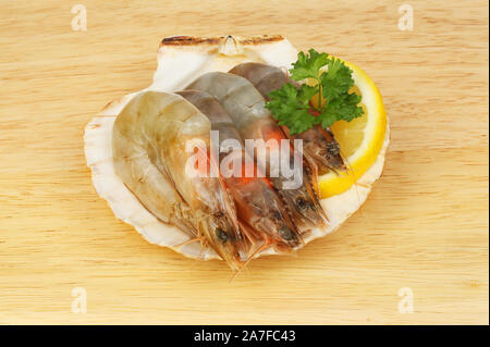 https://l450v.alamy.com/450v/2a7fc43/raw-tiger-prawns-with-lemon-and-parsley-in-a-scallop-shell-on-a-wooden-chopping-board-2a7fc43.jpg