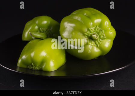 Green sweet pepper on a black plate, against a dark background Stock Photo