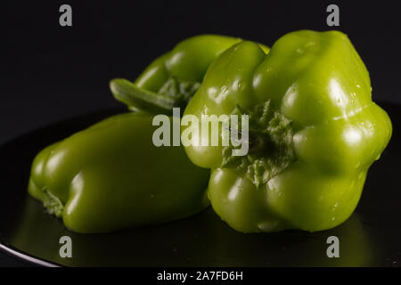 Green sweet pepper on a black plate, against a dark background Stock Photo