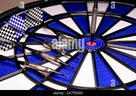 Traditional game of darts composed of target and darts in white and blue colors, with central point in red, and plastic material to avoid dangers and Stock Photo