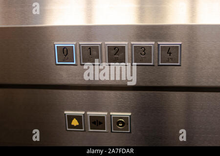 Keypad of a modern elevator for a building with four floors and ground floor, with buttons for alarm and on and off, as well as support of the door op Stock Photo