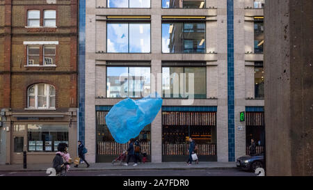 A blue plastic bag caught in the wind blows along a London street on a windy day. Stock Photo