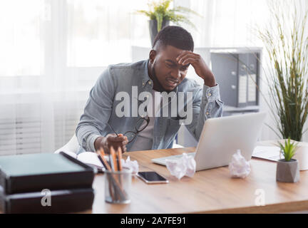 Annoyed black employee looking at laptop screen with despair Stock Photo