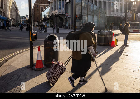 an elderly lady uses her walking stick to aid her way toward Charing Cross Road in London's west end on a bright winters morning.UK Stock Photo