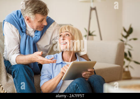 Modern senior spouses using digital tablet together Stock Photo