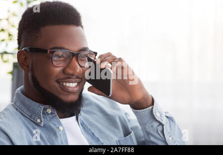 Portrait of handsome black guy in glasses talking on cellphone Stock Photo
