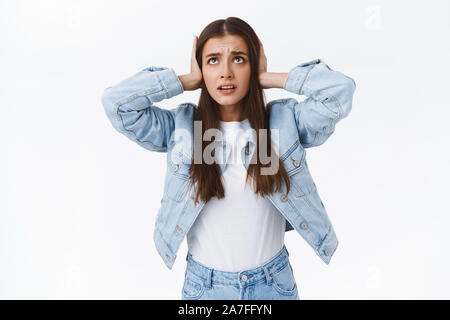 Girl cant stand hearing annoying neigbours arguing loud, cover ears and look up disturbed and stressed, standing bothered hate being interrupted with Stock Photo