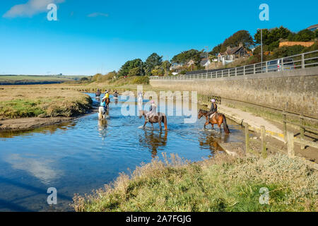 Pony trekking at low tide on the Gannel Estuary in Newquay in Cornwall. Stock Photo