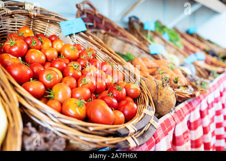close-up of fresh ripe organic tomatoes in wicker basket at market stall Stock Photo