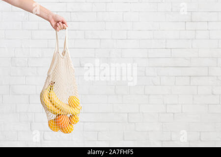 Woman holding Bananas and oranges in cotton reusable net bag Stock Photo