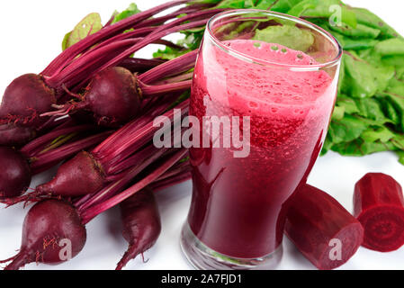 Beetroots with green leaves and fresh beet juice from organic farm in a glass on a white background. Stock Photo