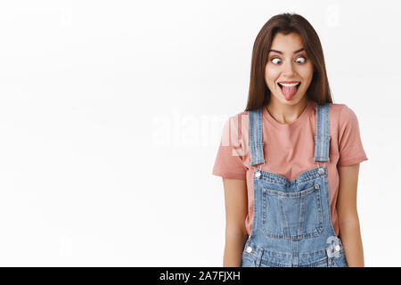 Funny and goofy carefree silly girl having fun, entertain friends showing hilarious faces, stick tongue and squinting, shifting eyes and smiling like Stock Photo