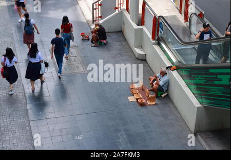Bangkok, Thailand-October 31 2019: A street vendor sitting on sidewalk in Siam Square selling handmade souvenir made from acacia wood, sitting close t Stock Photo
