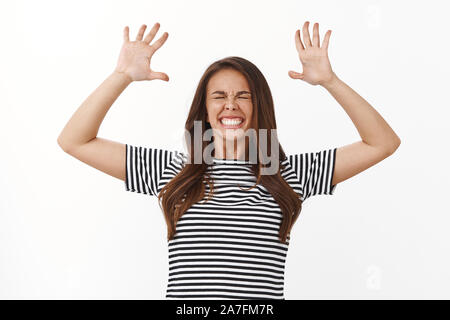 Extremely happy lucky young pretty woman in striped t-shirt feeling like on cloud nine, jumping accomplished and upbeat, celebrating victory, raise Stock Photo