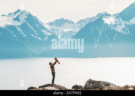 Father holding up baby hiking in mountains travel family adventure lifestyle vacations dad with kid outdoor journey in Norway Stock Photo