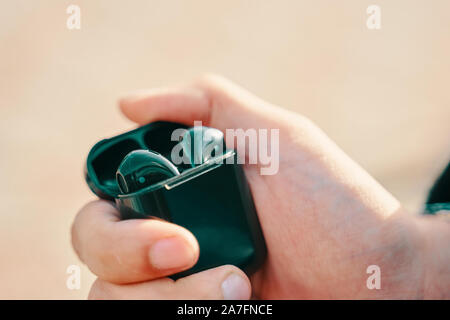 Bishkek, Kyrgyzstan - October 10, 2019: Man holding a custom black airpods from apple Stock Photo