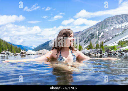 Happy girl woman swimming in hot springs water on Conundrum Creek Trail in Aspen, Colorado in 2019 summer in bathing suit with valley view