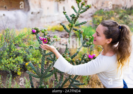 Young girl happy woman touching Cane Cholla cactus vivid pink flower on Main Loop trail in Bandelier National Monument in New Mexico in Los Alamos Stock Photo