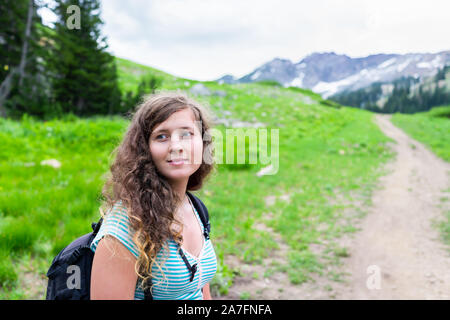 Albion Basin, Utah woman standing on summer dirt road meadows trail in 2019 in Wasatch mountains with rocky snowy Devil's Castle mountain Stock Photo