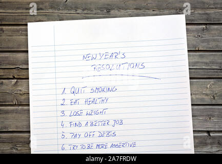 New Year's resolutions listed on a paper. Wooden background. Stock Photo