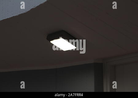 Single white ceiling light with led light, on the ceiling inside a corridor of the apartment. Stock Photo