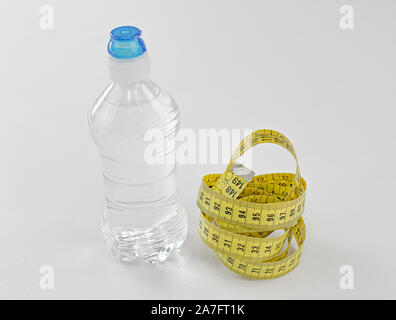 Bottle of mineral water without gas with sports cap and measuring yellow tape as essential elements for a diet Stock Photo