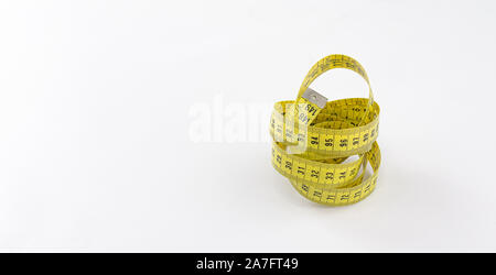 Yellow tape measure with black numbering rolled on itself and metallic terminal over white background Stock Photo