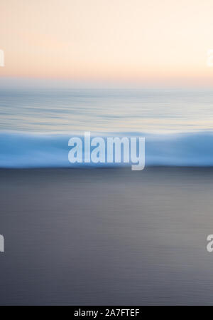 An abstract background nature image of a blurred wave in motion taken from a beach at sunset showing the beauty of the sea and representing calmness a Stock Photo