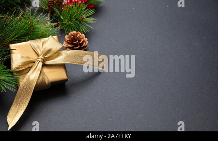 Christmas present. Xmas gift box shiny gold color against dark gray background, high angle, copy space Stock Photo