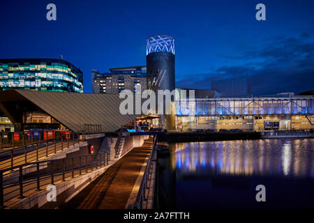 Night at MediacityUK Salford quays regenerated docks, Reid Architects designed Alchemist Media City with Lowry Theatre across the basin Stock Photo