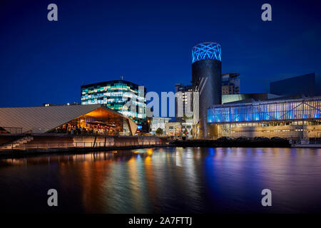 Night at MediacityUK Salford quays regenerated docks, Reid Architects designed Alchemist Media City with Lowry Theatre across the basin Stock Photo