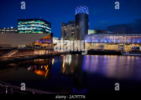 Night at MediacityUK Salford quays regenerated docks, Reid Architects designed Alchemist Media City with Lowry Theatre across the basin Stock Photo