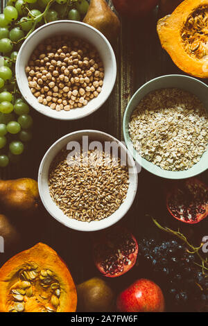 Autumnal fruit and healthy cereals background, typical fruit  of autumnal season, biologically cultivated, rounding bowls full of healthy cereals oats Stock Photo