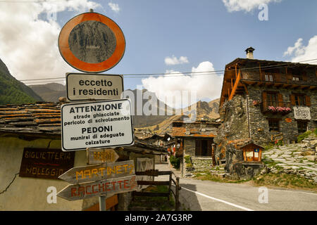 Glimpse of the old Alpine village of Chianale with the typical stone houses and street signs in a sunny summer day, Varaita Valley, Piedmont, Italy Stock Photo