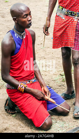 AMBOSELI, KENYA - MAY 2014: Portrait of young Maasai warrior showing how they make fire in a traditional way to guests visiting their village Stock Photo