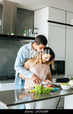 Man kissing girlfriend while she preparing breakfast in kitchen Stock Photo